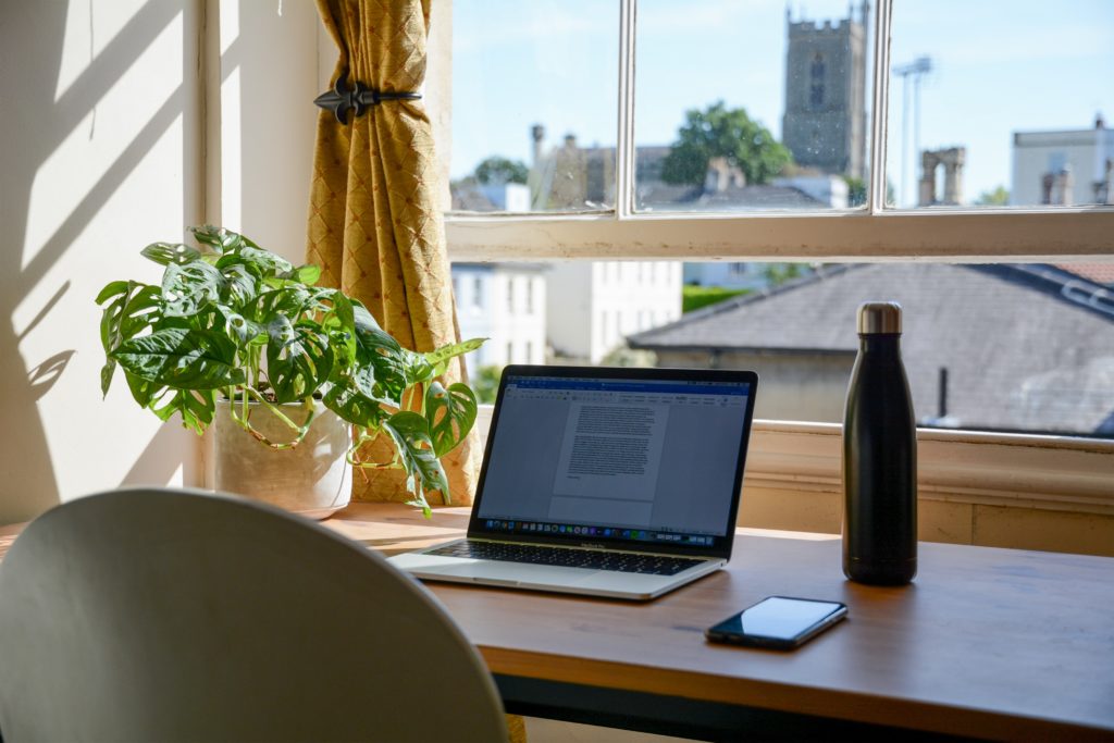 ordinateur portable ouverte sur bureau avec vue sur la ville, gourde et téléphone portable à côté