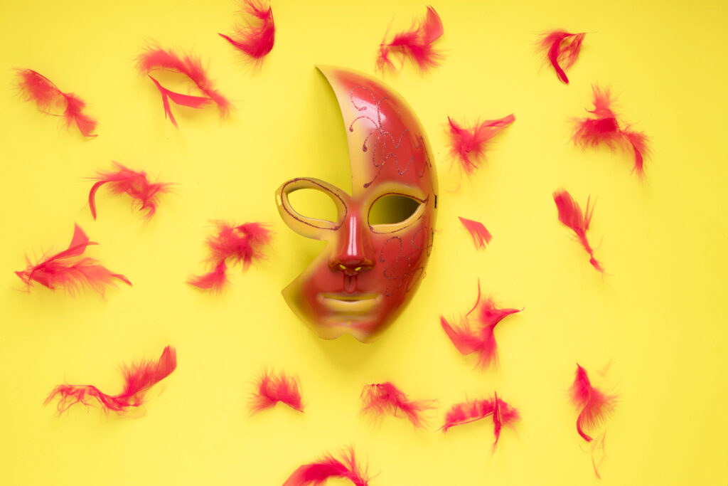 masque rouge sur fond jaune entouré de plumes rouges