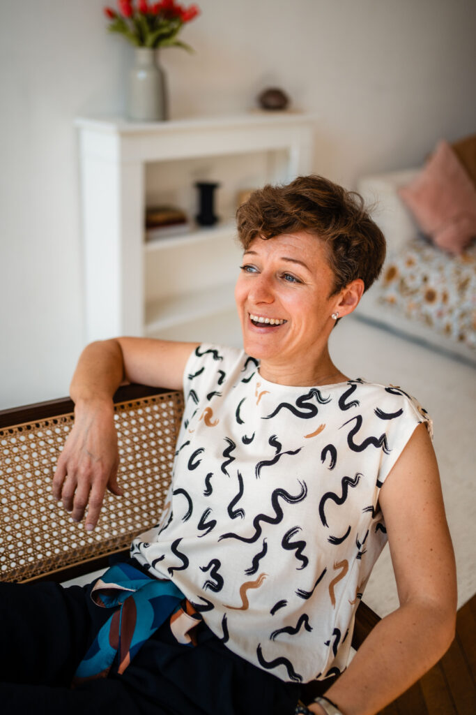 Cécile Routier Liot assise dans un fauteuil, de trois quart, heureuse et à l'écoute, en plein échange avec une autre personne