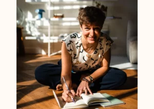Cécile Routier Liot Coach Professionnel assise par terre, prenant des notes, visage souriant